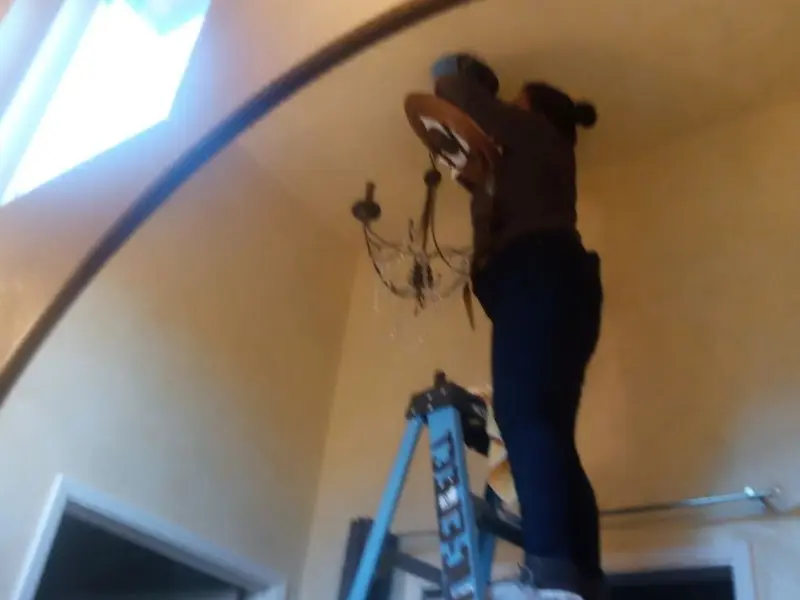 Electrician installing a chandelier in a Wendell residence